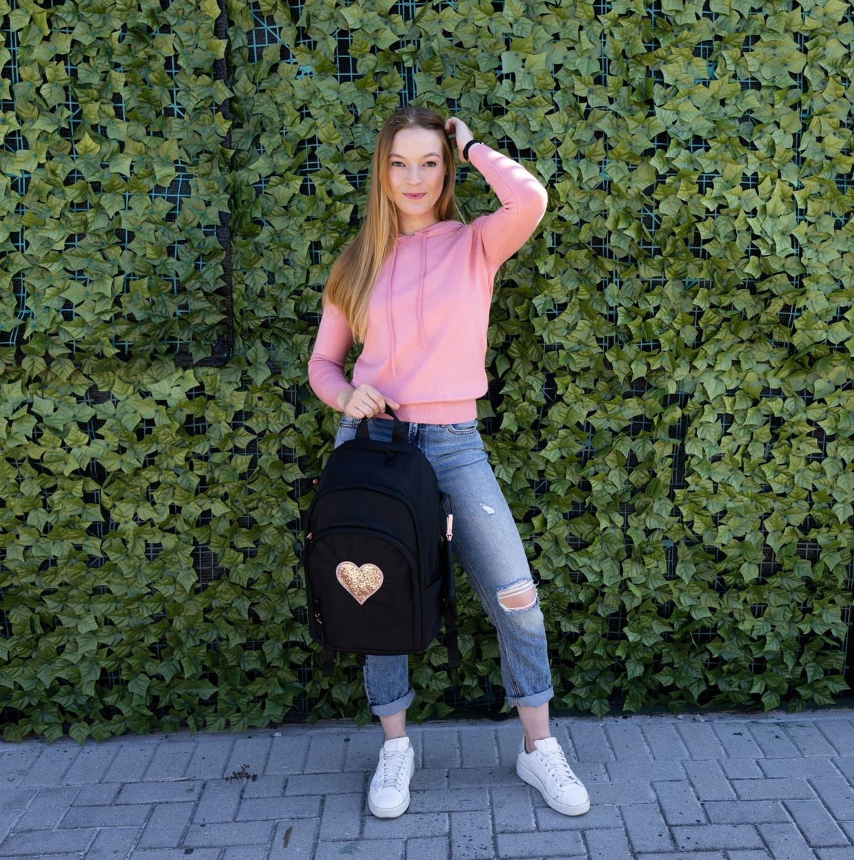Girl holding the Veltri Sport Delaire Backpack with the Heart Motif in Rose Gold