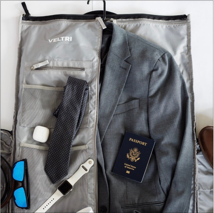 Interior view of Veltri Sport's Ellis Garment Duffle with all the travel belongings a man may use including a suit, tie, belt shoes, and passport