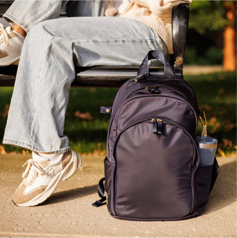 Veltri Sport Grande Backpack in navy placed beside a bench with a drink in the side pocket.