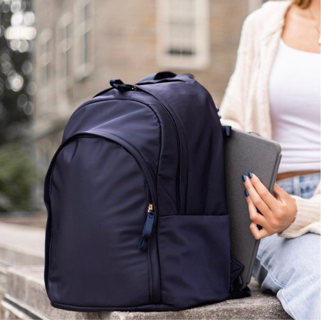 Woman placing a laptop into the padded laptop compartment of a Veltri Sport Delaire Backpack.