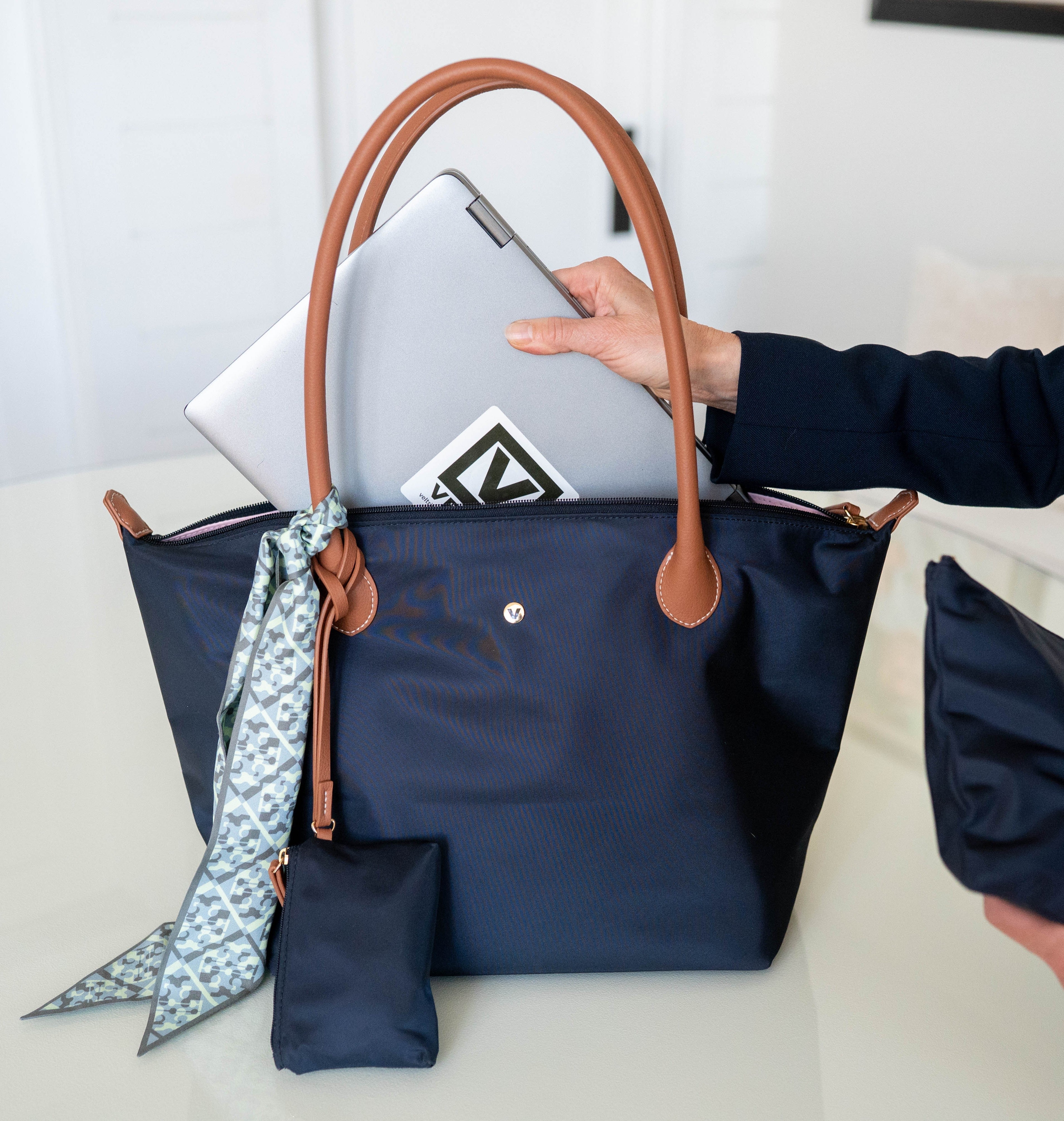 Veltri Sport's Campus Tote in Dark Navy with a girl placing her laptop into the zip top bag.