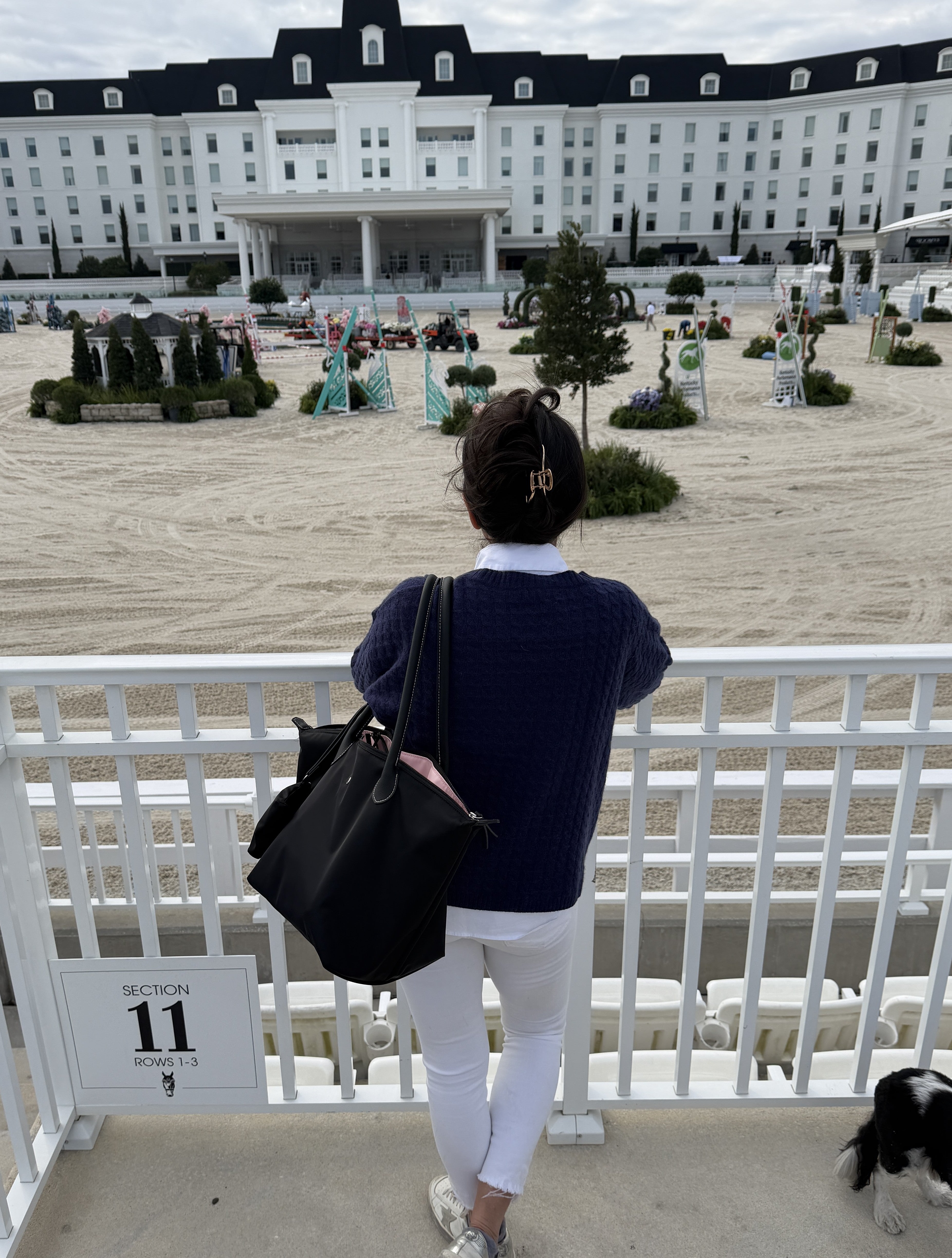 A woman carrying the Veltri Sport Campus Tote overlooking an equestrian show arena before the vent starts.