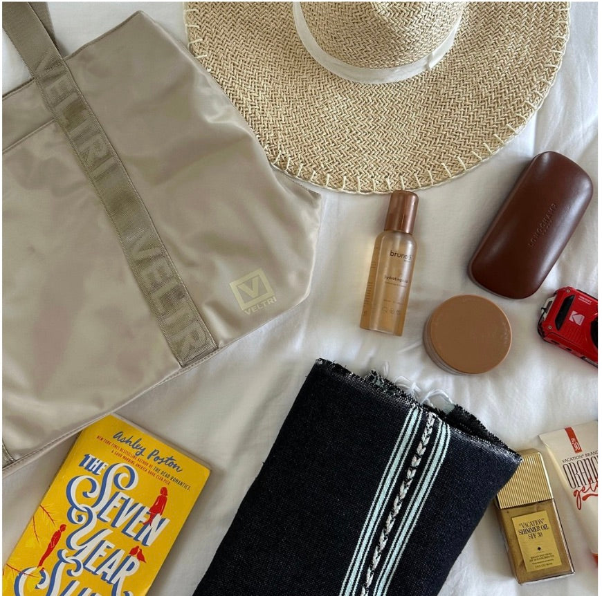 Veltri Sport Newport tote in sand against a white background amongst beach essentials.
