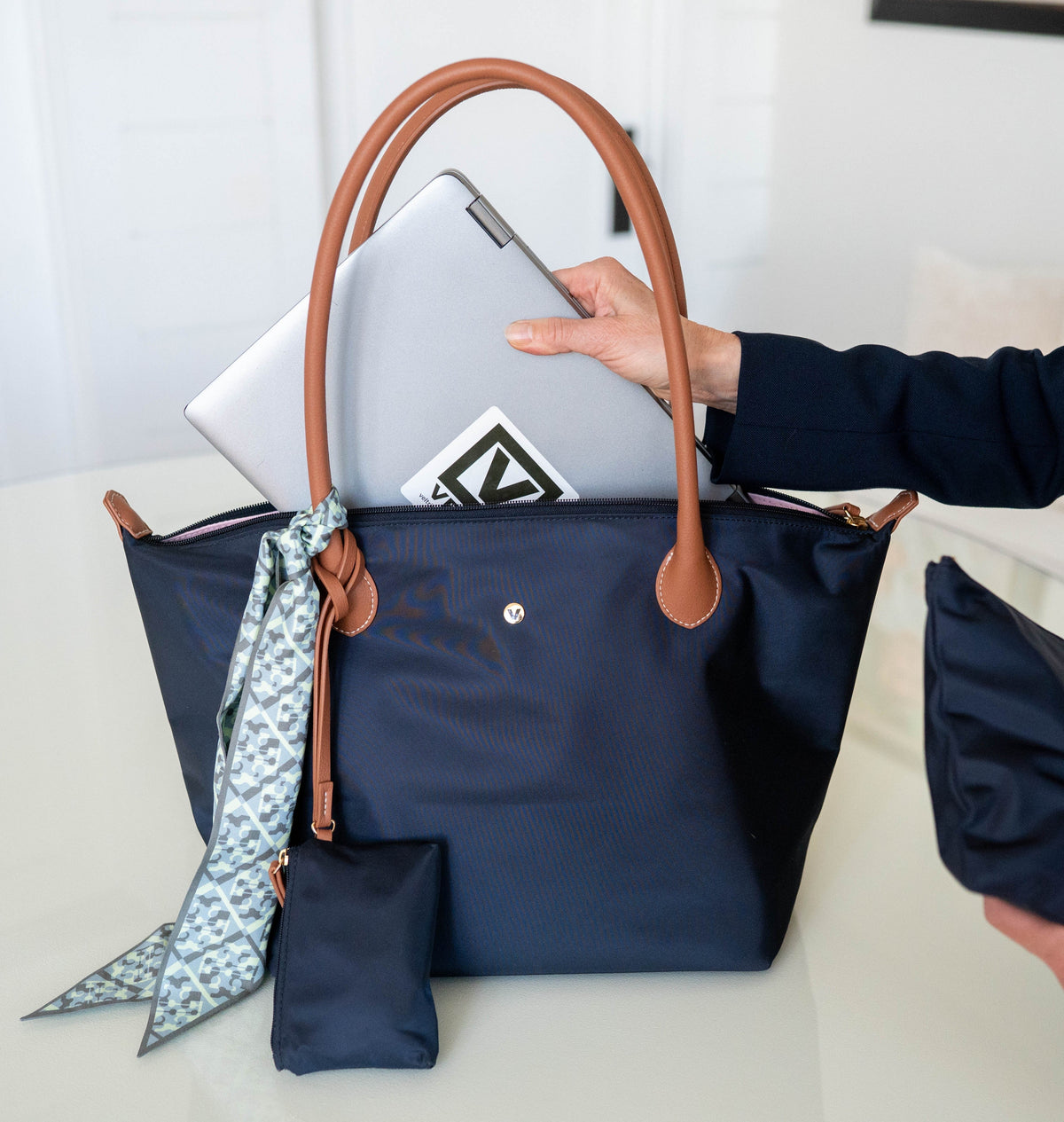 Veltri Sport's Campus Tote in Dark Navy with a girl placing her laptop into the zip top bag.