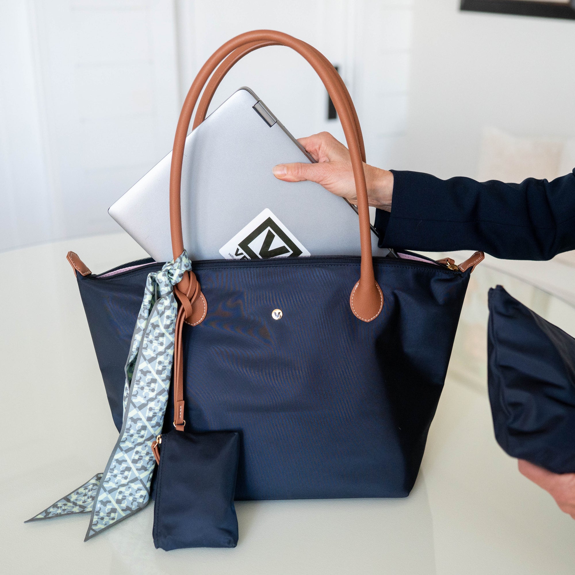 Veltri Sport Campus Tote holding a laptop, with a person's hand visible, on a light background.